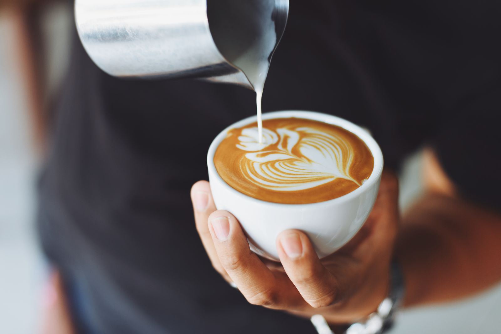 Barista pouring latte art into a cup
