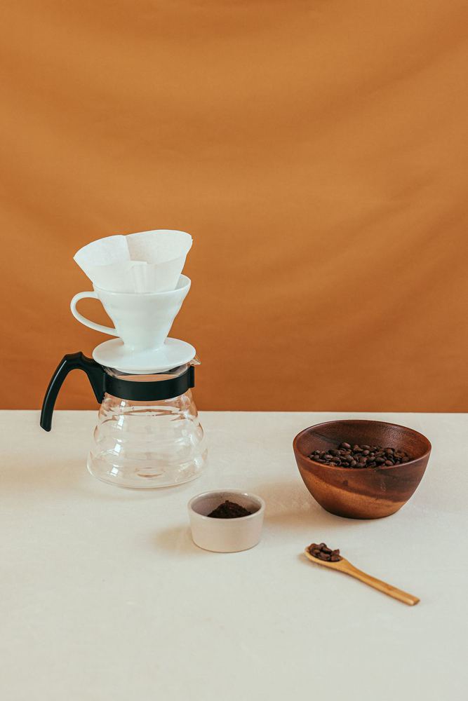 Pour-over brewer, filters and beans on a counter