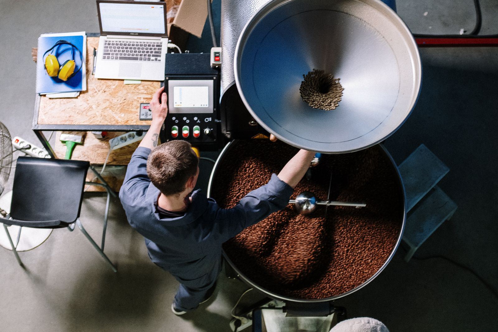 Overhead view of the roaster loading the drum, laptop logging the curve