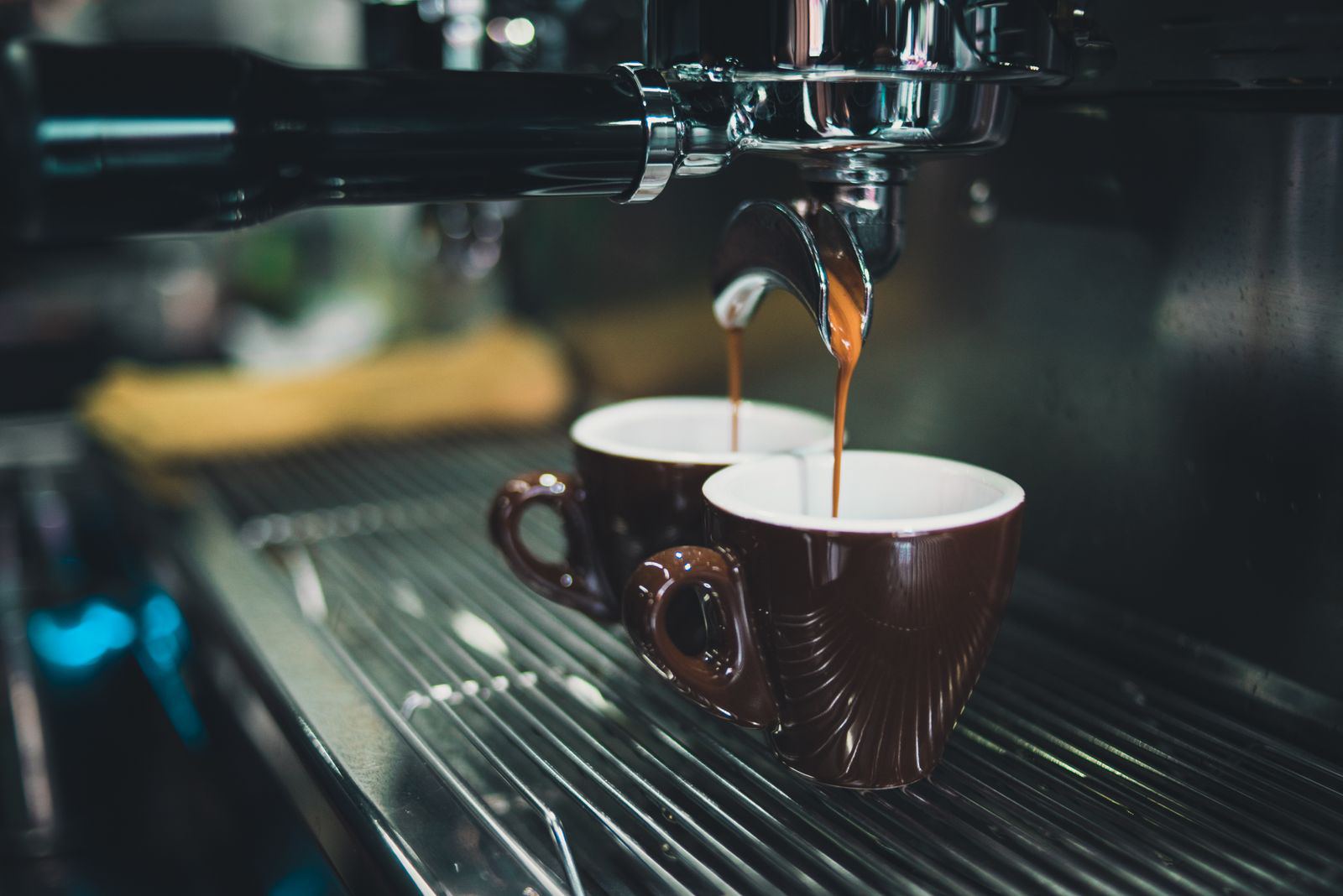 Espresso pulling into two brown cups on a machine