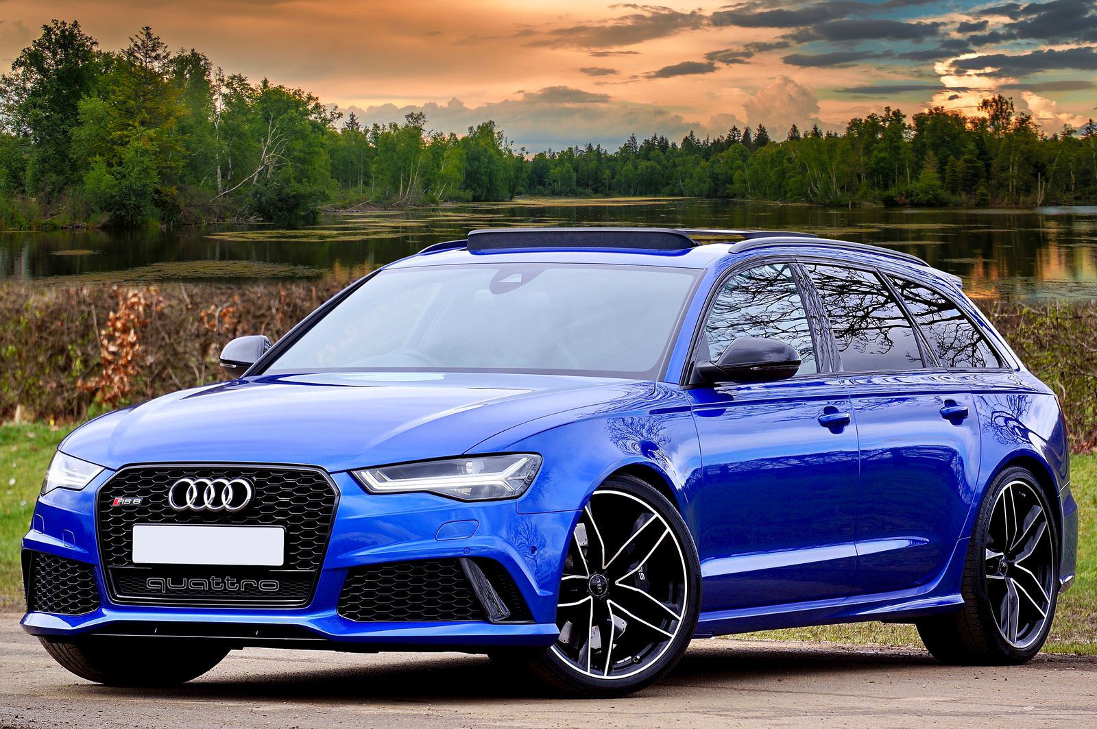 Blue Audi RS 6 Avant parked by a lake at dusk